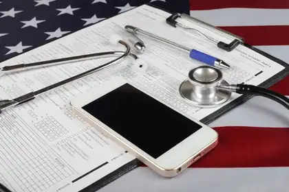 Stethoscope and phone on a health form over an American flag